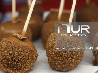 Caramel candy apples are covered with chocolate and sugar at a carnival in Markham, Ontario, Canada, on October 5, 2024. (