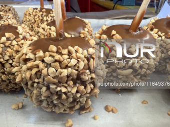 Caramel candy apples are covered with nuts at a carnival in Markham, Ontario, Canada, on October 5, 2024. (