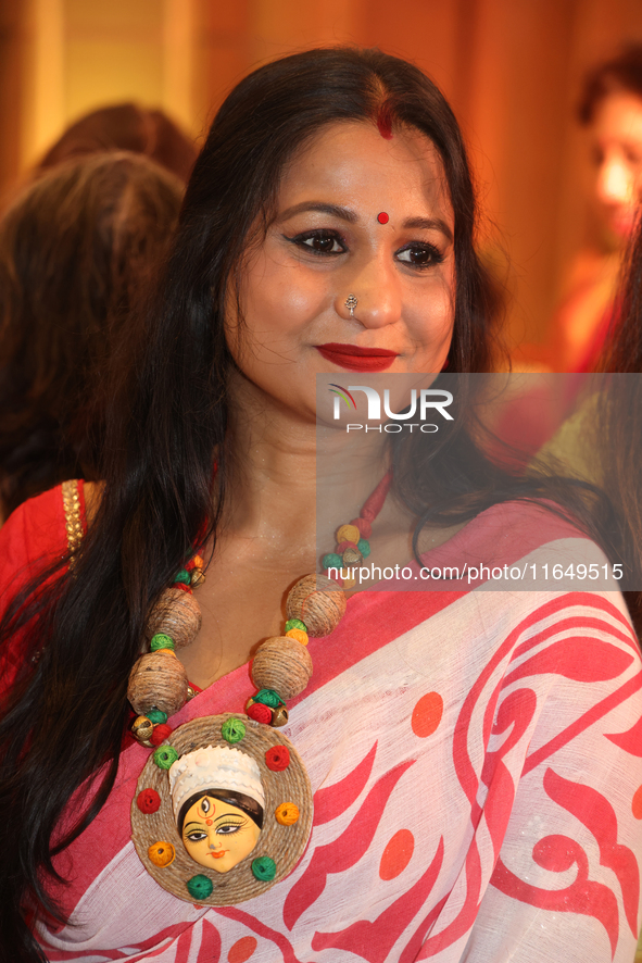 A Bengali Hindu woman wears a necklace with an image of the Goddess Durga while waiting to offer prayers during the Durga Puja festival at a...