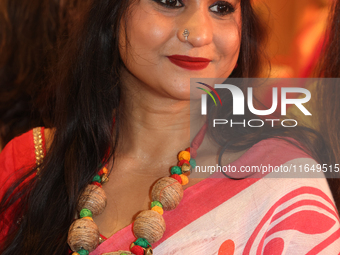 A Bengali Hindu woman wears a necklace with an image of the Goddess Durga while waiting to offer prayers during the Durga Puja festival at a...