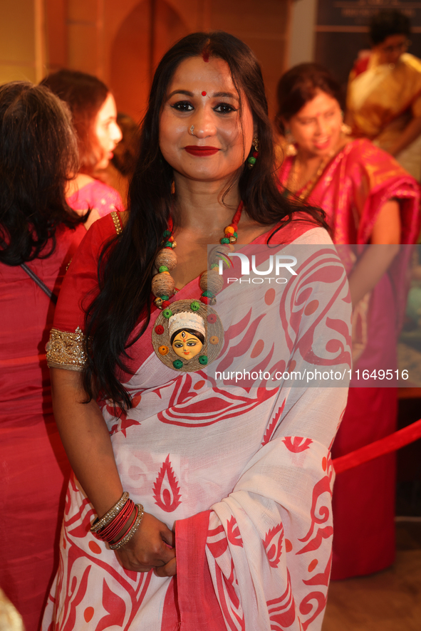 A Bengali Hindu woman wears a necklace with an image of the Goddess Durga while waiting to offer prayers during the Durga Puja festival at a...