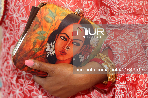 A Bengali Hindu woman holds a fancy handbag while waiting to offer prayers during the Durga Puja festival at a pandal in Mississauga, Ontari...