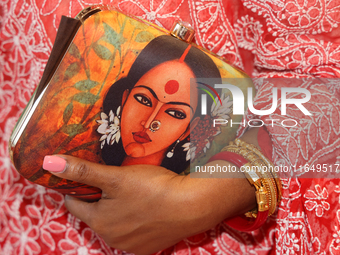 A Bengali Hindu woman holds a fancy handbag while waiting to offer prayers during the Durga Puja festival at a pandal in Mississauga, Ontari...