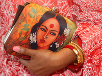 A Bengali Hindu woman holds a fancy handbag while waiting to offer prayers during the Durga Puja festival at a pandal in Mississauga, Ontari...