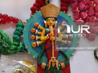 A necklace with a talisman featuring the Goddess Durga is for sale at a jewelry stall during the Durga Puja festival at a pandal (temporary...