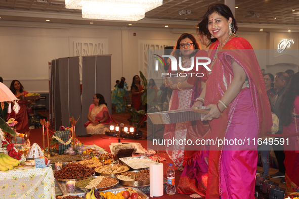 Bengali Hindu women carry trays of offerings during the Durga Puja festival at a pandal (temporary temple) in Mississauga, Ontario, Canada,...