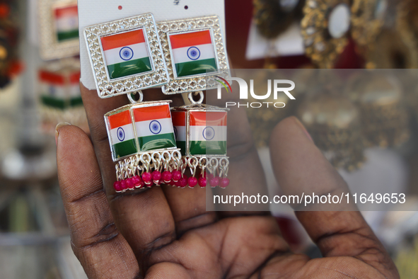 A woman looks at a pair of earrings decorated with the flag of India at a small stall selling costume jewelry and temple jewelry during the...