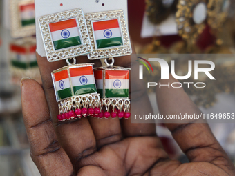 A woman looks at a pair of earrings decorated with the flag of India at a small stall selling costume jewelry and temple jewelry during the...