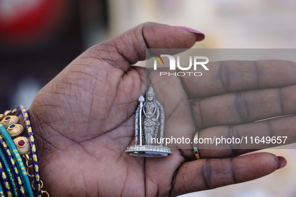 A woman holds a small pure silver idol of Lord Murugan at a small stall selling various puja items during the Sree Ganesh Chaturthi Mahotsav...