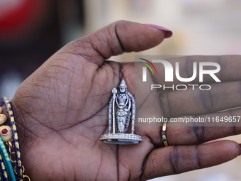 A woman holds a small pure silver idol of Lord Murugan at a small stall selling various puja items during the Sree Ganesh Chaturthi Mahotsav...