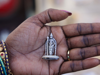 A woman holds a small pure silver idol of Lord Murugan at a small stall selling various puja items during the Sree Ganesh Chaturthi Mahotsav...