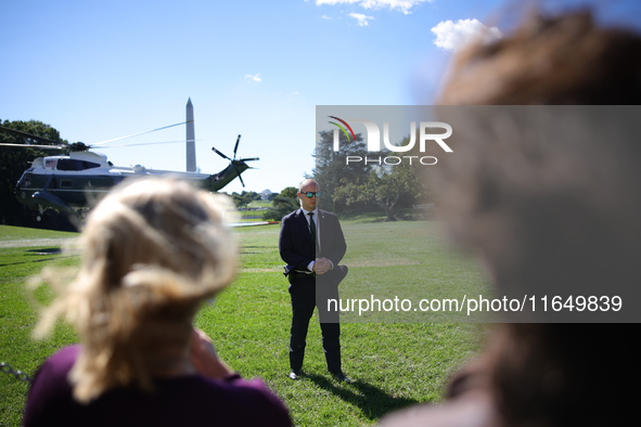 A U.S. Secret Service officer stands guard on the South Lawn of the White House on October 8, 2024 as Marine One prepares to take off with P...