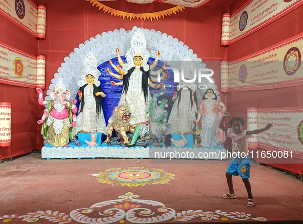 A little girl dances next to a Durga idol inside a pendant or a temporary platform on the occasion of the Durga Puja festival in Kolkata, In...