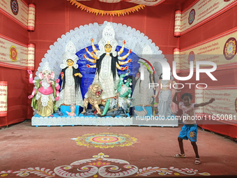 A little girl dances next to a Durga idol inside a pendant or a temporary platform on the occasion of the Durga Puja festival in Kolkata, In...