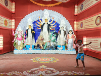 A little girl dances next to a Durga idol inside a pendant or a temporary platform on the occasion of the Durga Puja festival in Kolkata, In...