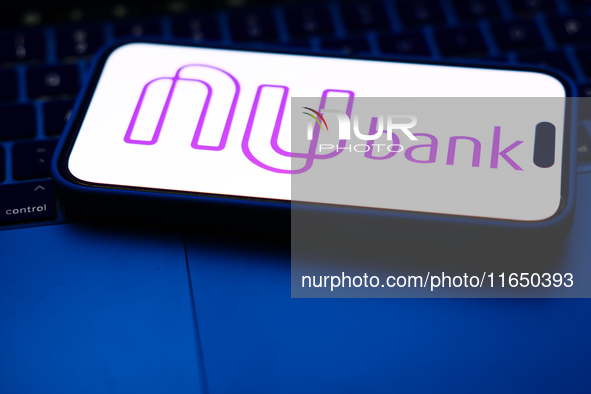 A laptop keyboard and Nubank logo displayed on a phone screen are seen in this illustration photo taken in Poland on October 8, 2024. 