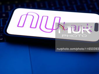 A laptop keyboard and Nubank logo displayed on a phone screen are seen in this illustration photo taken in Poland on October 8, 2024. (