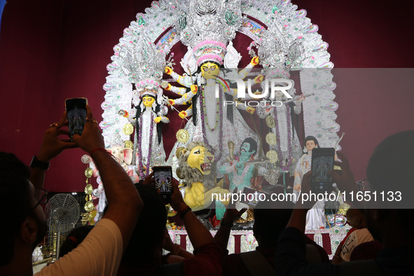 Devotees take mobile pictures of Hindu goddess Durga inside a puja pandal, a temporary structure set up during the Durga Puja festival in Ko...