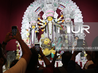 Devotees take mobile pictures of Hindu goddess Durga inside a puja pandal, a temporary structure set up during the Durga Puja festival in Ko...