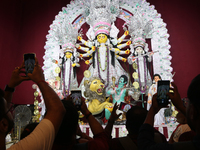 Devotees take mobile pictures of Hindu goddess Durga inside a puja pandal, a temporary structure set up during the Durga Puja festival in Ko...