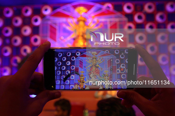 Devotees take mobile pictures of Hindu goddess Durga inside a puja pandal, a temporary structure set up during the Durga Puja festival in Ko...