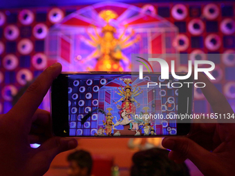 Devotees take mobile pictures of Hindu goddess Durga inside a puja pandal, a temporary structure set up during the Durga Puja festival in Ko...