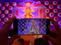 Devotees take mobile pictures of Hindu goddess Durga inside a puja pandal, a temporary structure set up during the Durga Puja festival in Ko...