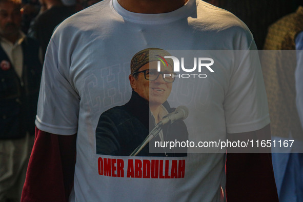 A supporter of the Jammu and Kashmir National Conference (JKNC) party wears a t-shirt with pictures of party leader Omar Abdullah at his res...