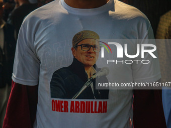 A supporter of the Jammu and Kashmir National Conference (JKNC) party wears a t-shirt with pictures of party leader Omar Abdullah at his res...