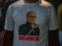 A supporter of the Jammu and Kashmir National Conference (JKNC) party wears a t-shirt with pictures of party leader Omar Abdullah at his res...