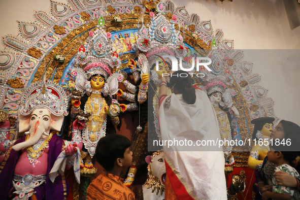 A Hindu married woman puts on a gold nose ring as part of rituals before she offers prayer to an idol of the Hindu goddess Durga inside a 18...