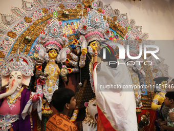 A Hindu married woman puts on a gold nose ring as part of rituals before she offers prayer to an idol of the Hindu goddess Durga inside a 18...