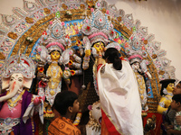 A Hindu married woman puts on a gold nose ring as part of rituals before she offers prayer to an idol of the Hindu goddess Durga inside a 18...