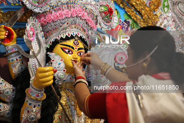 A Hindu married woman puts on a gold nose ring as part of rituals before she offers prayer to an idol of the Hindu goddess Durga inside a 18...