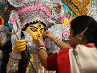 A Hindu married woman puts on a gold nose ring as part of rituals before she offers prayer to an idol of the Hindu goddess Durga inside a 18...