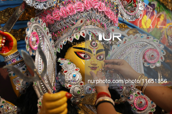 A Hindu married woman puts on a gold nose ring as part of rituals before she offers prayer to an idol of the Hindu goddess Durga inside a 18...