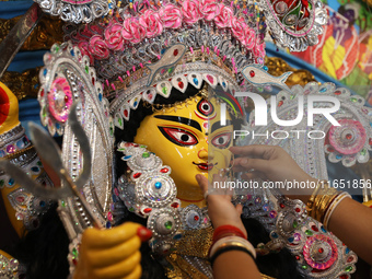 A Hindu married woman puts on a gold nose ring as part of rituals before she offers prayer to an idol of the Hindu goddess Durga inside a 18...