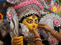 A Hindu married woman puts on a gold nose ring as part of rituals before she offers prayer to an idol of the Hindu goddess Durga inside a 18...