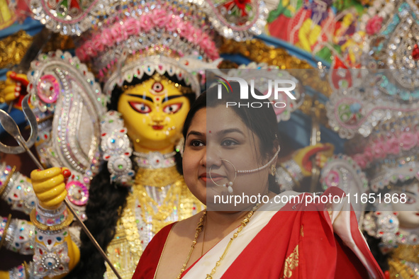 A Hindu married woman gestures after putting on a gold nose ring as part of rituals before she offers prayer to an idol of the Hindu goddess...