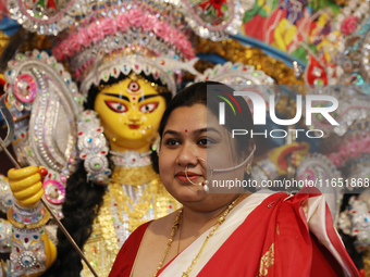 A Hindu married woman gestures after putting on a gold nose ring as part of rituals before she offers prayer to an idol of the Hindu goddess...