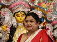 A Hindu married woman gestures after putting on a gold nose ring as part of rituals before she offers prayer to an idol of the Hindu goddess...