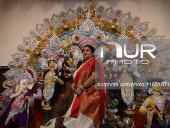 A Hindu married woman gestures after putting on a gold nose ring as part of rituals before she offers prayer to an idol of the Hindu goddess...