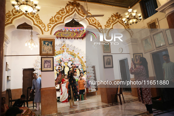 Children take a selfie after a Hindu married woman gestures by putting on a gold nose ring as part of rituals before she offers prayer to an...