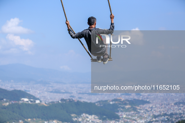 A Nepali man swings facing the Kathmandu Valley with the arrival of the fortnightly festival of Dashain in Kathmandu, Nepal, on October 9, 2...