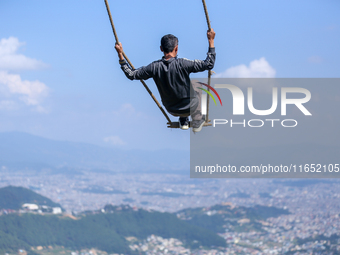 A Nepali man swings facing the Kathmandu Valley with the arrival of the fortnightly festival of Dashain in Kathmandu, Nepal, on October 9, 2...