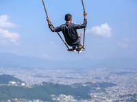 A Nepali man swings facing the Kathmandu Valley with the arrival of the fortnightly festival of Dashain in Kathmandu, Nepal, on October 9, 2...