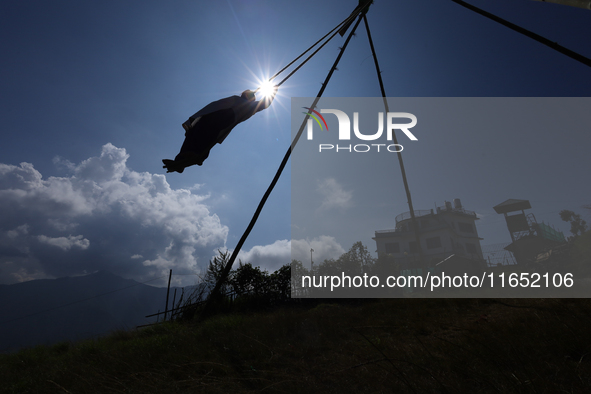 A Nepali woman is silhouetted against the sun as she plays on a swing installed on a hillside surrounding Kathmandu Valley with the arrival...