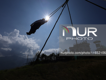 A Nepali woman is silhouetted against the sun as she plays on a swing installed on a hillside surrounding Kathmandu Valley with the arrival...