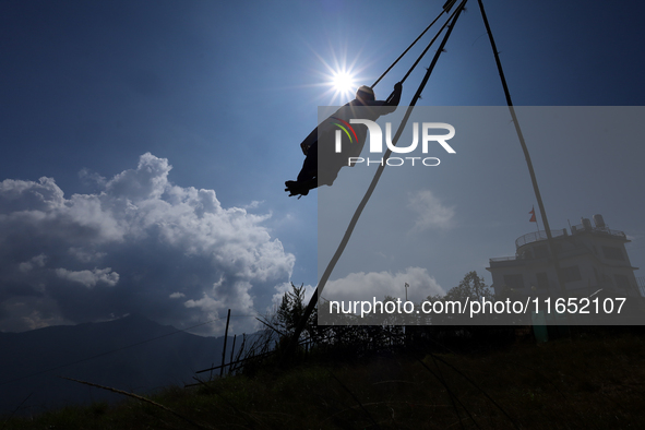 A Nepali woman is silhouetted against the sun as she plays on a swing installed on a hillside surrounding Kathmandu Valley with the arrival...