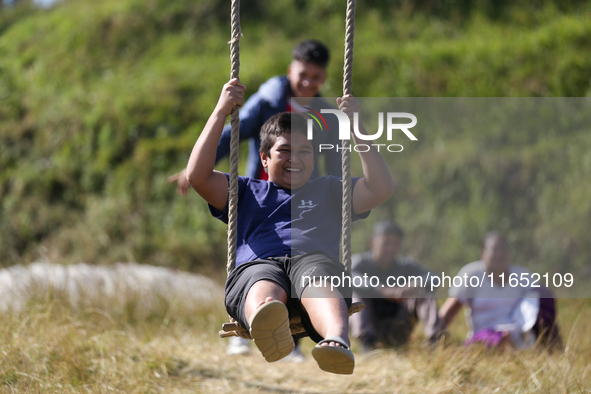 A Nepali boy gestures as he plays on a swing installed on a hillside surrounding Kathmandu Valley with the arrival of the fortnightly festiv...